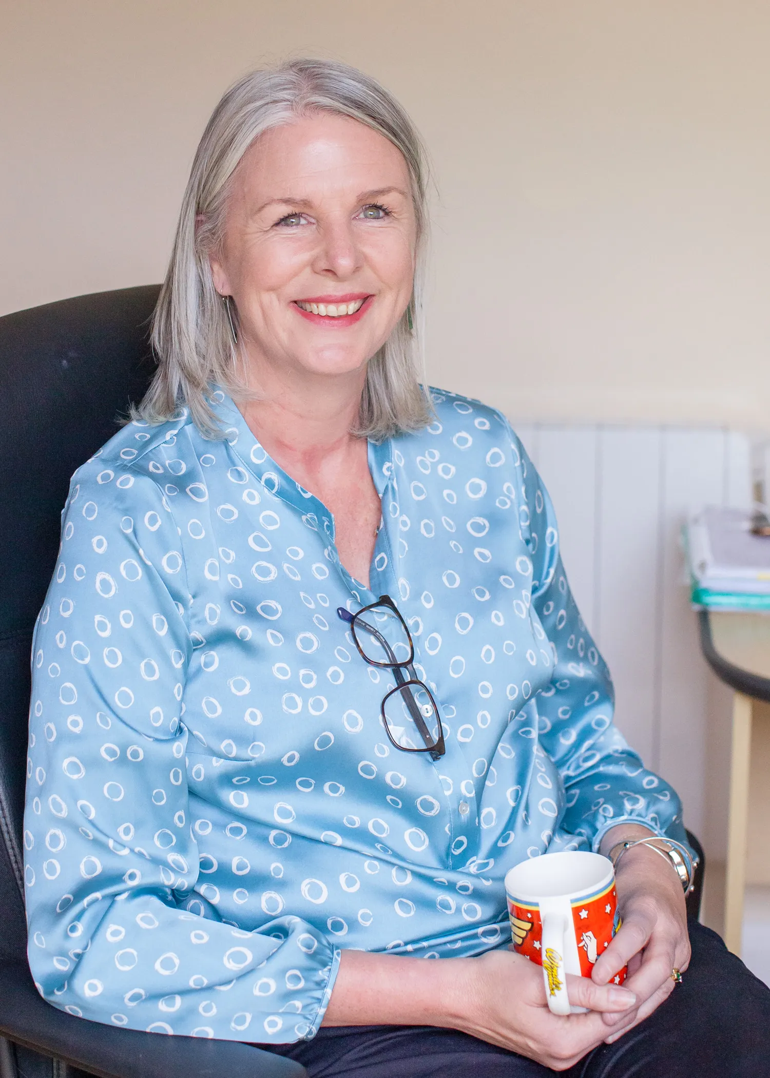 Nichola Lynagh seated with a cup of coffee, glasses in hand